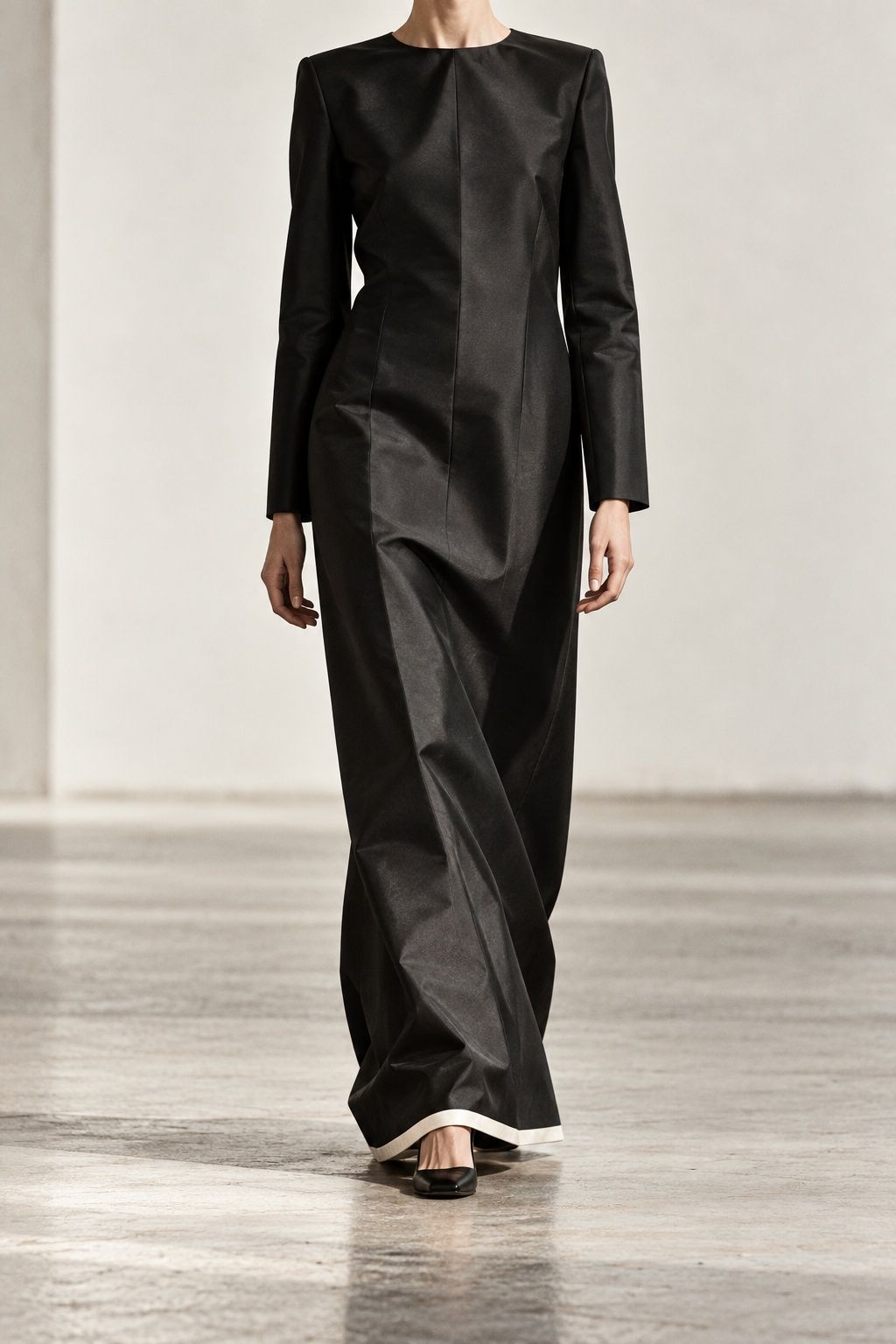 Floor-length black silk faille column dress on a model seen from the shoulders down, sharp fold lines catching the light